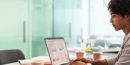 Marketing analyst reviewing predictive lead scores on a laptop in a bright meeting room